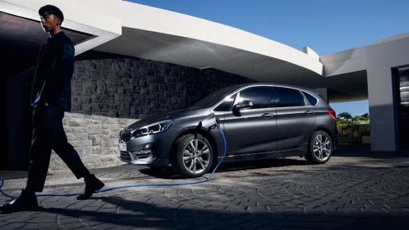 Imagine cu trei sferturi din partea laterală a unui BMW 225xe Active Tourer F45 plug-in hybrid în faţa unei clădiri Imagine cu trei sferturi din partea laterală a unui BMW 225xe Active Tourer F45 plug-in hybrid în faţa unei clădiri, cu un model