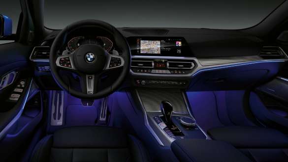 Lumina ambientală a BMW Seria 3 Sedan. Imagine frontală cu partea de habitaclu a conducătorului auto din BMW Seria 3 Sedan, cu spaţiul pentru picioare cu lumină ambientală albastră.