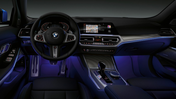 Lumina ambientală a BMW Seria 3 Sedan. Imagine frontală cu partea de habitaclu a conducătorului auto din BMW Seria 3 Sedan, cu spaţiul pentru picioare cu lumină ambientală albastră.