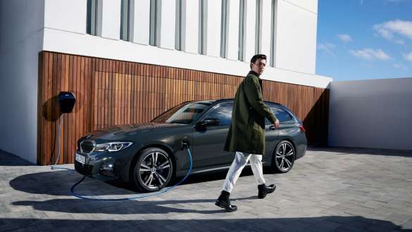 Imagine cu trei sferturi din partea laterală a unui BMW Seria 3 Touring plug-in hybrid 2021 G21 conectat la BMW Wallbox Imagine cu trei sferturi din partea laterală a unui BMW Seria 3 Touring plug-in hybrid 2021 G21 conectat la BMW Wallbox