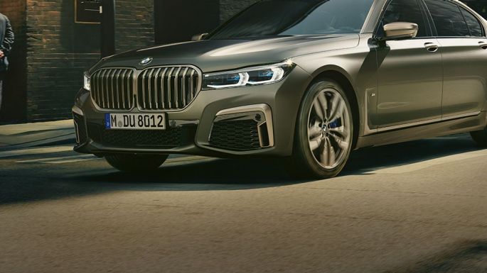 BMW M760Li xDrive într-un peisaj urban Perspectivă laterală din faţă asupra BMW M760Li xDrive rulând pe stradă într-un peisaj urban