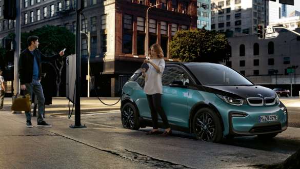 BMW i3 I01 2018 la o staţie publică de încărcare Cuplu încărcându-şi automobilul BMW i3 I01 2018 Albastru Ridge Mountain cu detalii în Gri Frozen la o staţie publică de încărcare