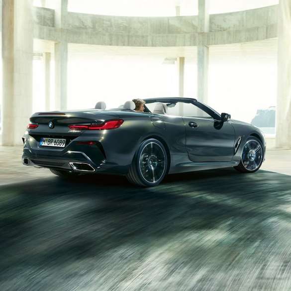 Imagine cu trei sferturi din partea spate a BMW M850i xDrive Cabriolet. Imagine cu trei sferturi din partea spate a BMW M850i xDrive Cabriolet în Gri Dravit metalizat cu soft-top-ul deschis, rulând in interiorul unei clădiri din beton.