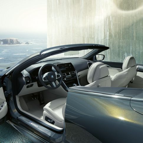 Interiorul BMW M850i xDrive Cabriolet. BMW M850i xDrive Cabriolet în Gri Dravit metalizat cu soft-top-ul deschis şi interiorul cu volan M îmbrăcat în piele şi ornamente din piele Merino în Alb Ivory de la BMW Individual.
