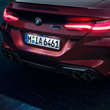 Imagine în prim-plan cu partea spate a BMW M8 Competition Cabriolet. Imagine în prim-plan cu partea spate a BMW M8 Competition Cabriolet în Roşu Motegi metalizat cu stopuri cu tehnologie LED şi inscripţie „M8 Competition”.