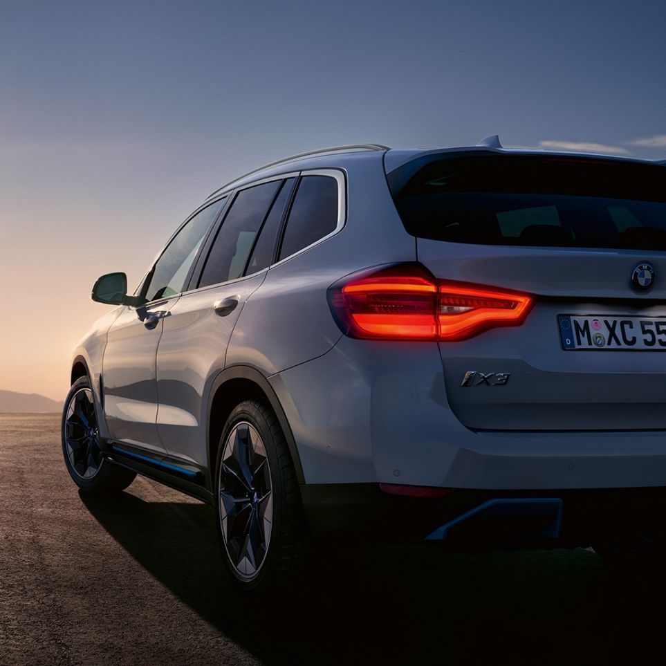 Imagine cu trei sferturi din partea spate a BMW iX3, G08, pe şosea Imagine cu trei sferturi din partea spate a BMW iX3, G08, 2020, în Alb Mineral metalizat, pe şosea