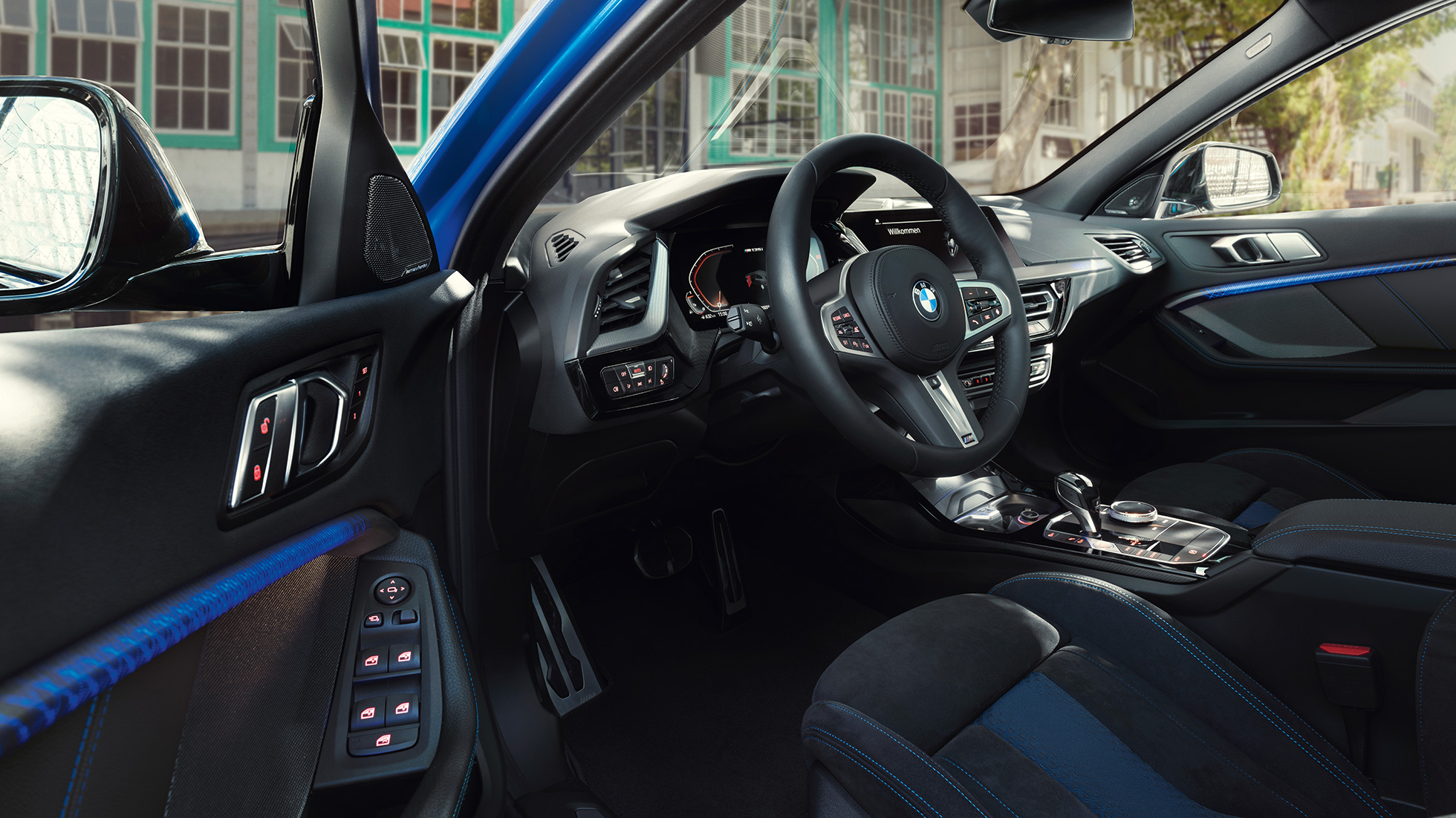 Habitaclul BMW Seria 1. Imagine cu habitaclul BMW Seria 1 cu volan M îmbrăcat în piele, în timp ce portiera de pe partea conducătorului auto este deschisă.