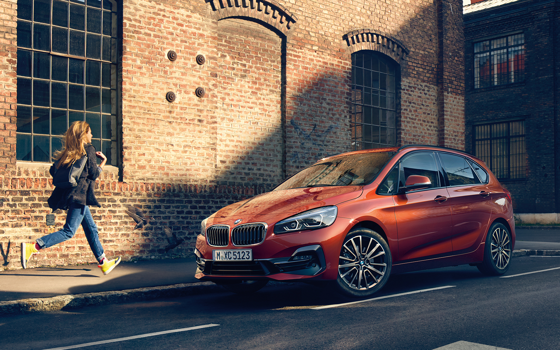Imagine cu BMW Seria 2 Active Tourer într-un peisaj urban şi cu o femeie alergând înspre acesta. Imagine cu BMW Seria 2 Active Tourer într-un peisaj urban şi cu o femeie alergând înspre acesta.