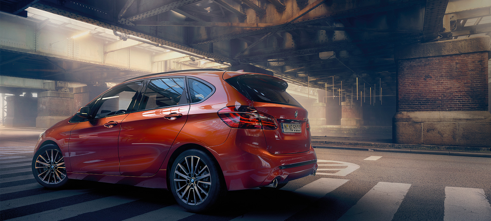 Imagine cu partea laterală a BMW Seria 2 Active Tourer Imagine cu partea laterală a BMW Seria 2 Active Tourer, F45, în Portocaliu Sunset metalizat, staţionat într-o sală