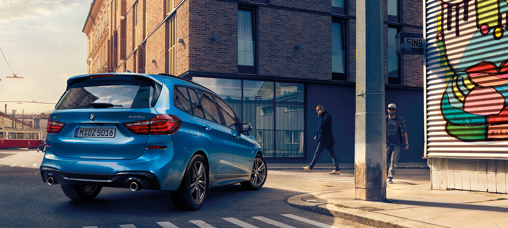 Imagine din unghi înalt a unui bărbat stâng lângă un BMW Seria 2 Gran Tourer, F46 Facelift 2018, în Albastru Misano metalizat