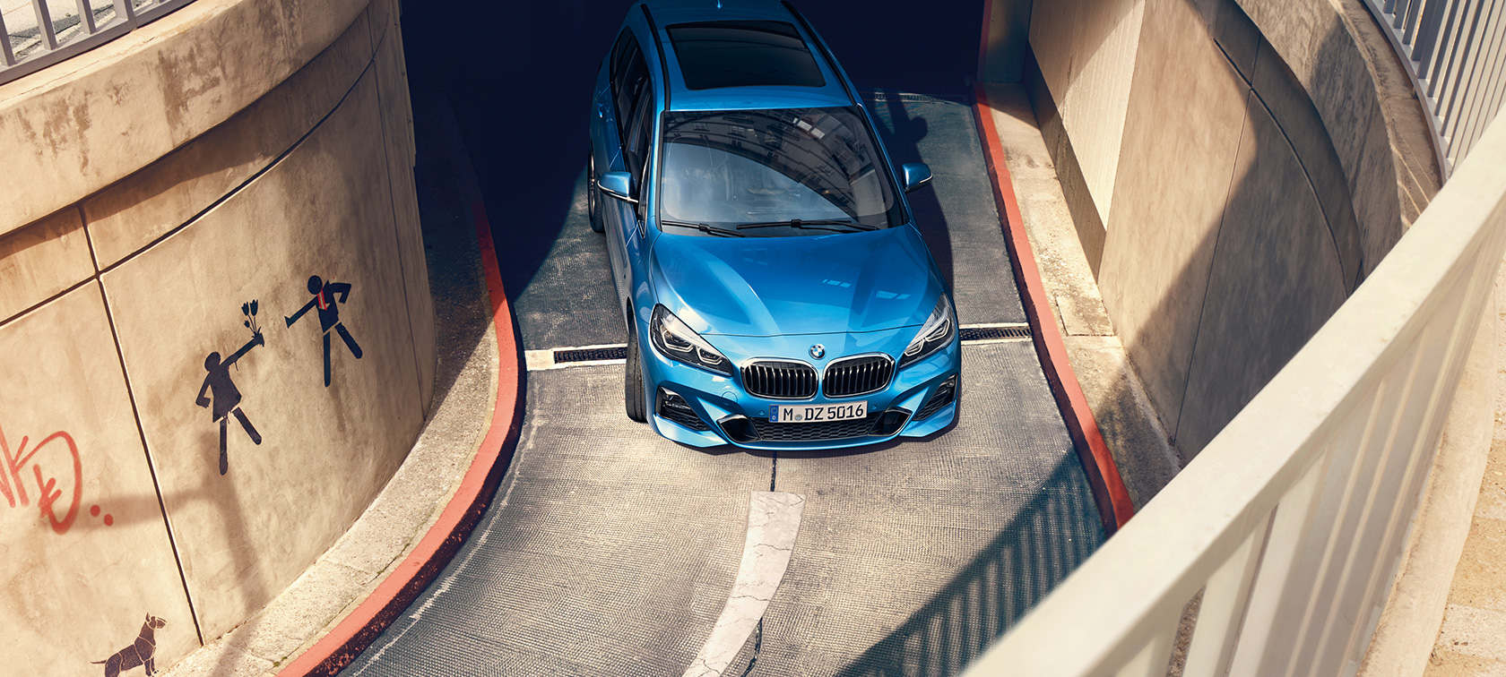 Imagine din unghi înalt cu BMW Seria 2 Gran Tourer, F46, în Albastru Misano metalizat, rulând într-o parcare cu etaj