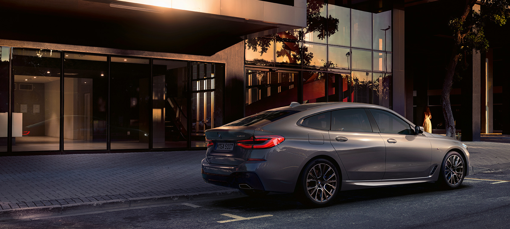 BMW Seria 6 Gran Turismo, G32, 2020 Imagine cu partea laterală spate a BMW 640i xDrive Gran Turismo, G32, 2020, în Gri Bernina, parcat în faţa unei clădiri
