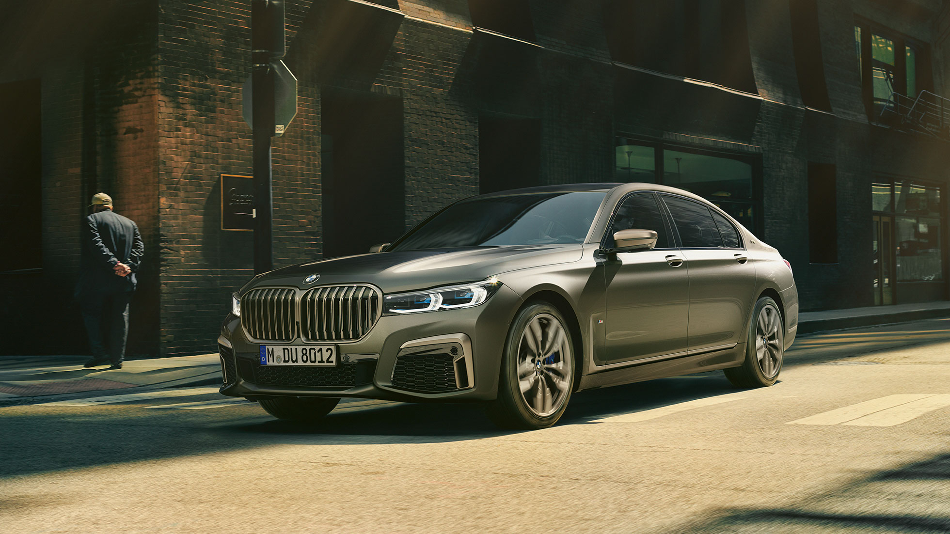 BMW M760Li xDrive într-un peisaj urban Perspectivă laterală din faţă asupra BMW M760Li xDrive rulând pe stradă într-un peisaj urban