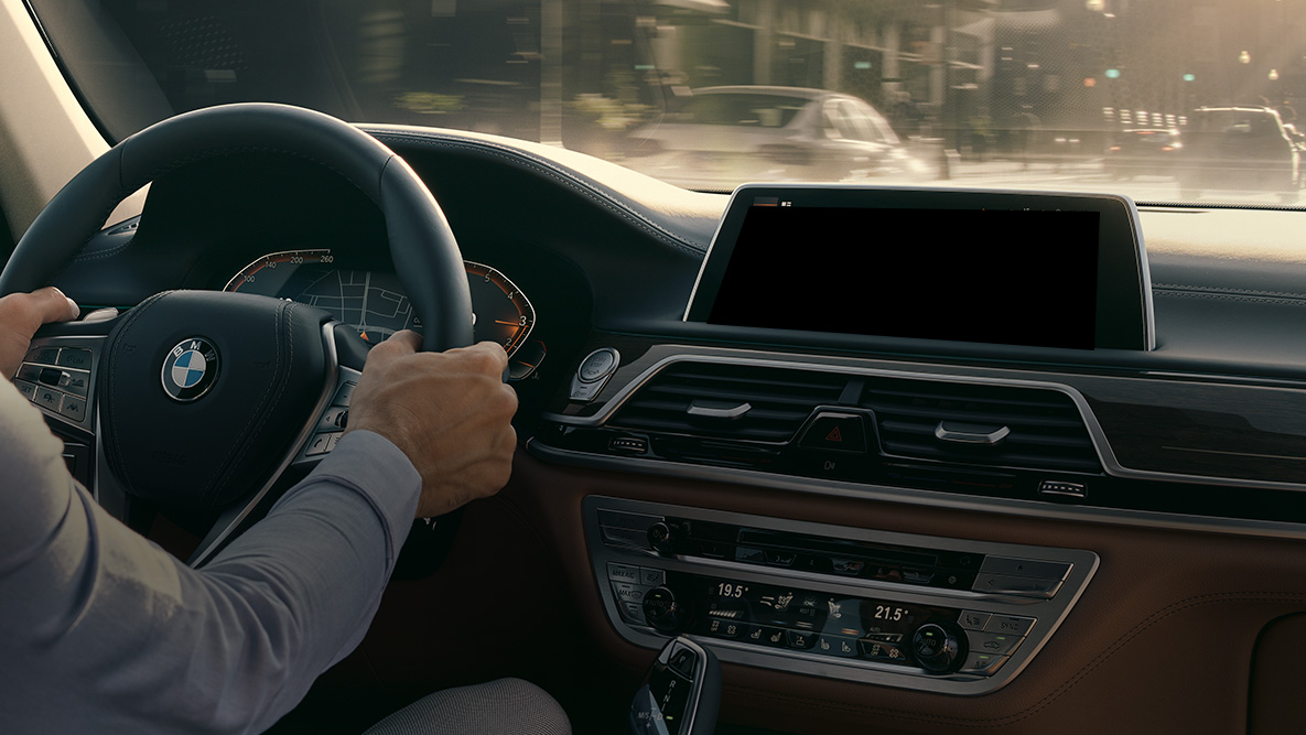 „BMW Intelligent Personal Assistant” „BMW Intelligent Personal Assistant”: un bărbat conduce un automobil BMW, imagine în prim-plan cu „BMW Live Cockpit Professional”