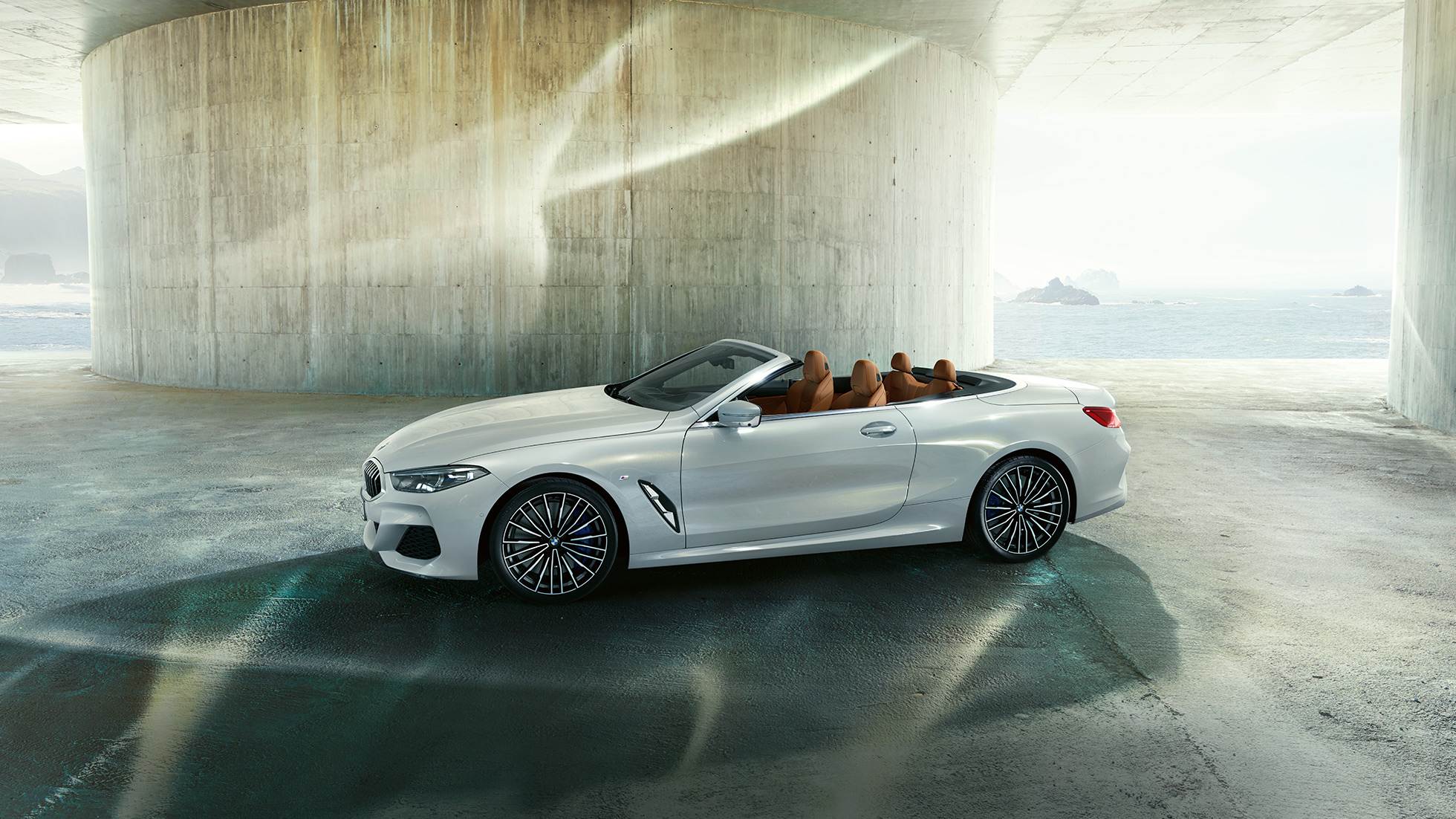 Imagine din lateral cu BMW M850i xDrive în Alb Mineral metalizat şi cu soft-top-ul deschis. Imagine din lateral cu BMW M850i xDrive în Alb Mineral metalizat şi cu soft-top-ul deschis.