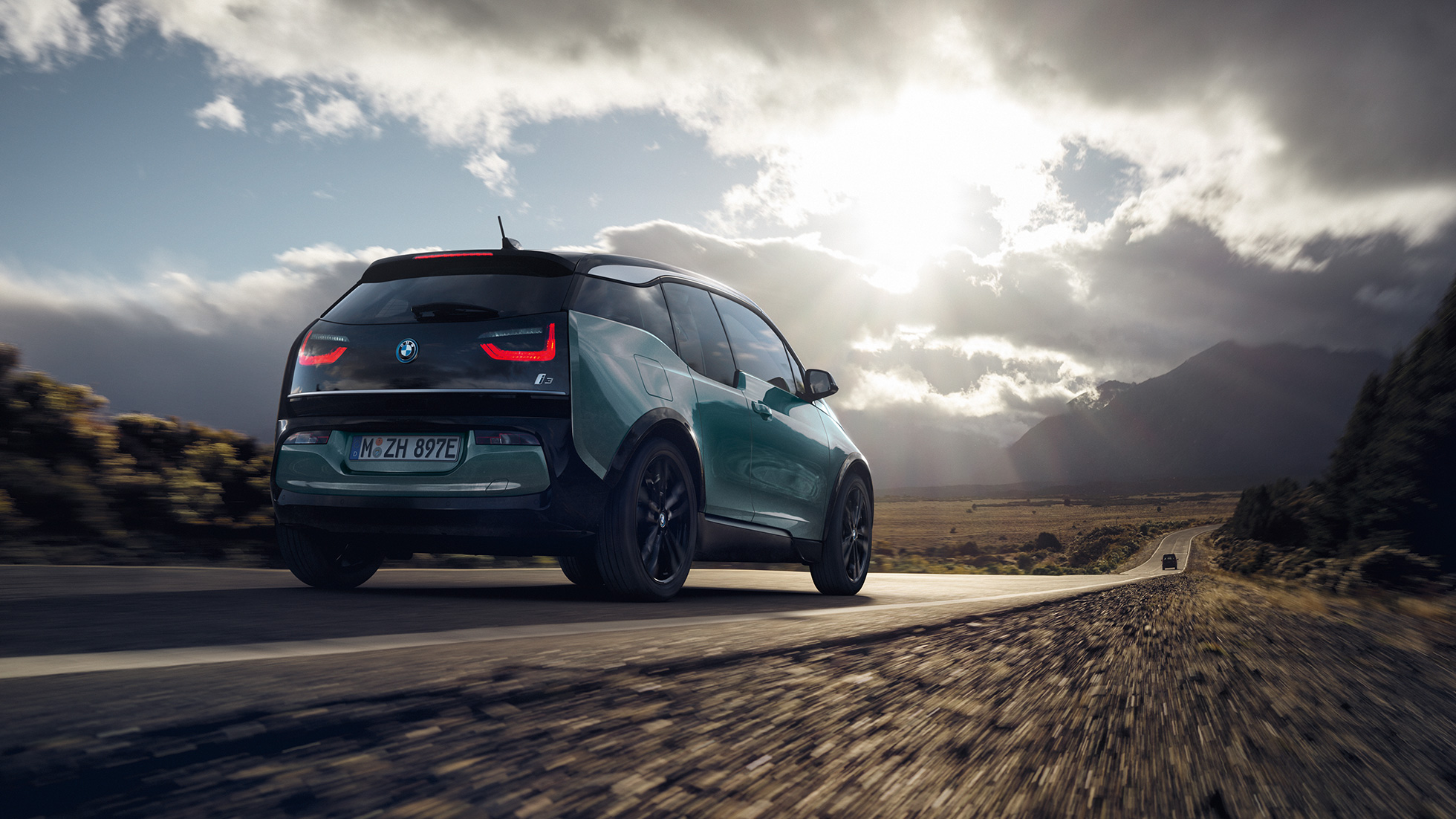 Imagine cu trei sferturi din partea spate a BMW i3, 2018, rulând pe autostradă Imagine cu trei sferturi din partea spate a BMW i3, I01, 2018, în Bej Jucaro cu detalii în Gri Frozen metalizat, rulând pe autostradă