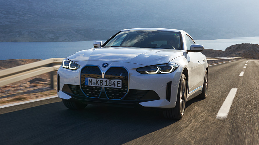 Imagine cu trei sferturi din partea frontală a unui BMW i4 eDrive40 G26 2021 în timp ce se deplasează Imagine cu trei sferturi din partea frontală a unui BMW i4 eDrive40 G26 2021 Alb Mineral în timp ce se deplasează