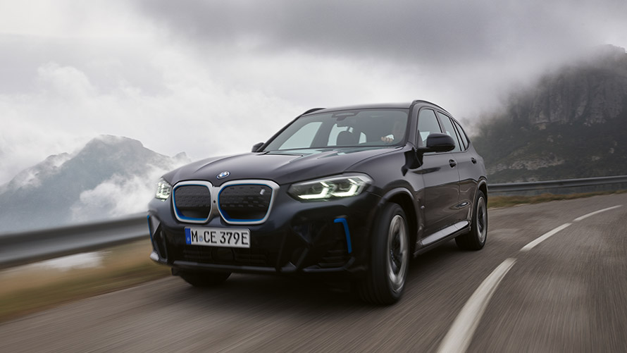 Imagine cu trei sferturi din partea laterală a BMW iX3 G08 din prima generaţie în timp ce se deplasează Imagine cu trei sferturi din partea laterală a unui BMW Seria i BMW iX3 G08 din prima generaţie în timp ce se deplasează