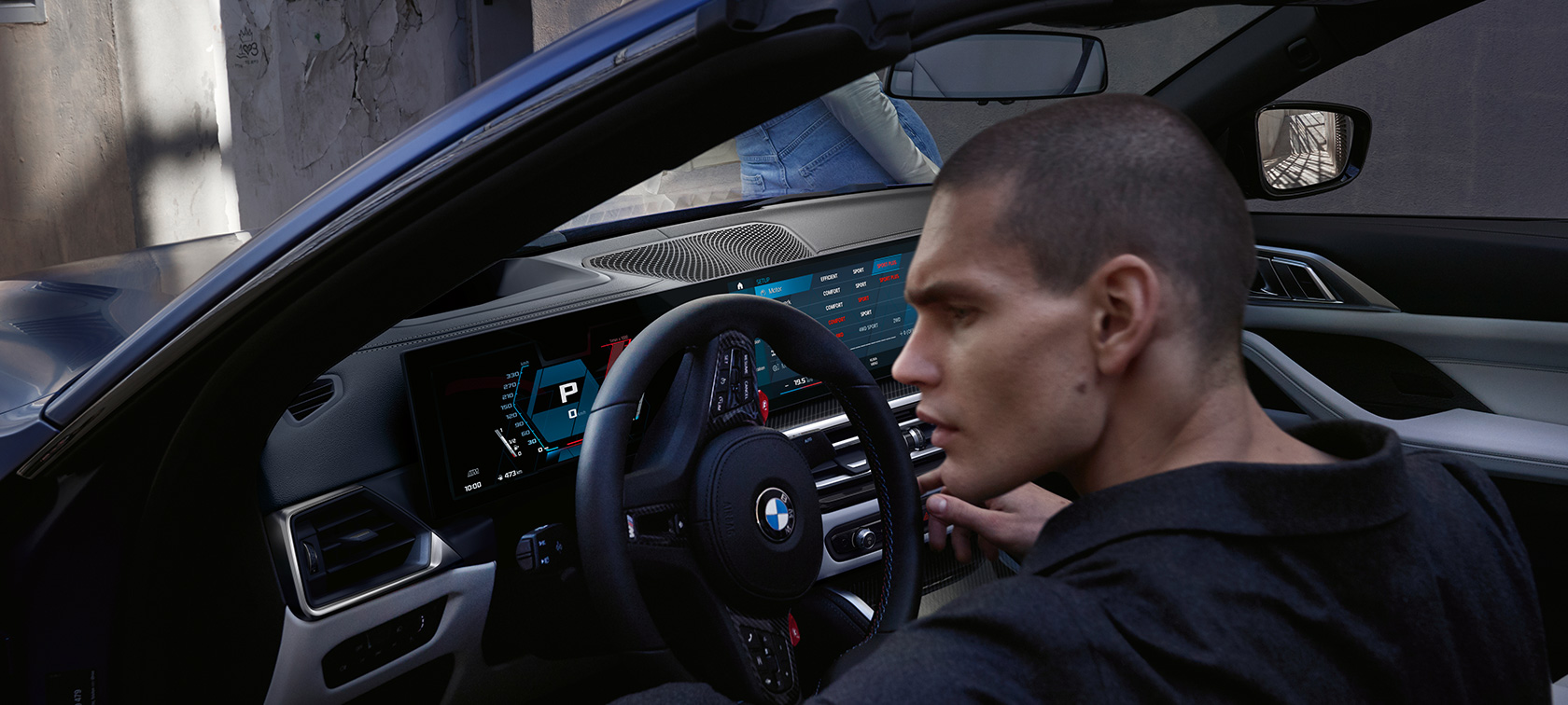 Imagine cu habitaclul BMW M4 Competition Cabriolet G83 2021 cu xDrive M Imagine cu habitaclul BMW M4 Competition Cabriolet G83 2021 cu xDrive M, în BMW Individual Albastru Frozen Portimao, cu portiera deschisă şi model bărbat