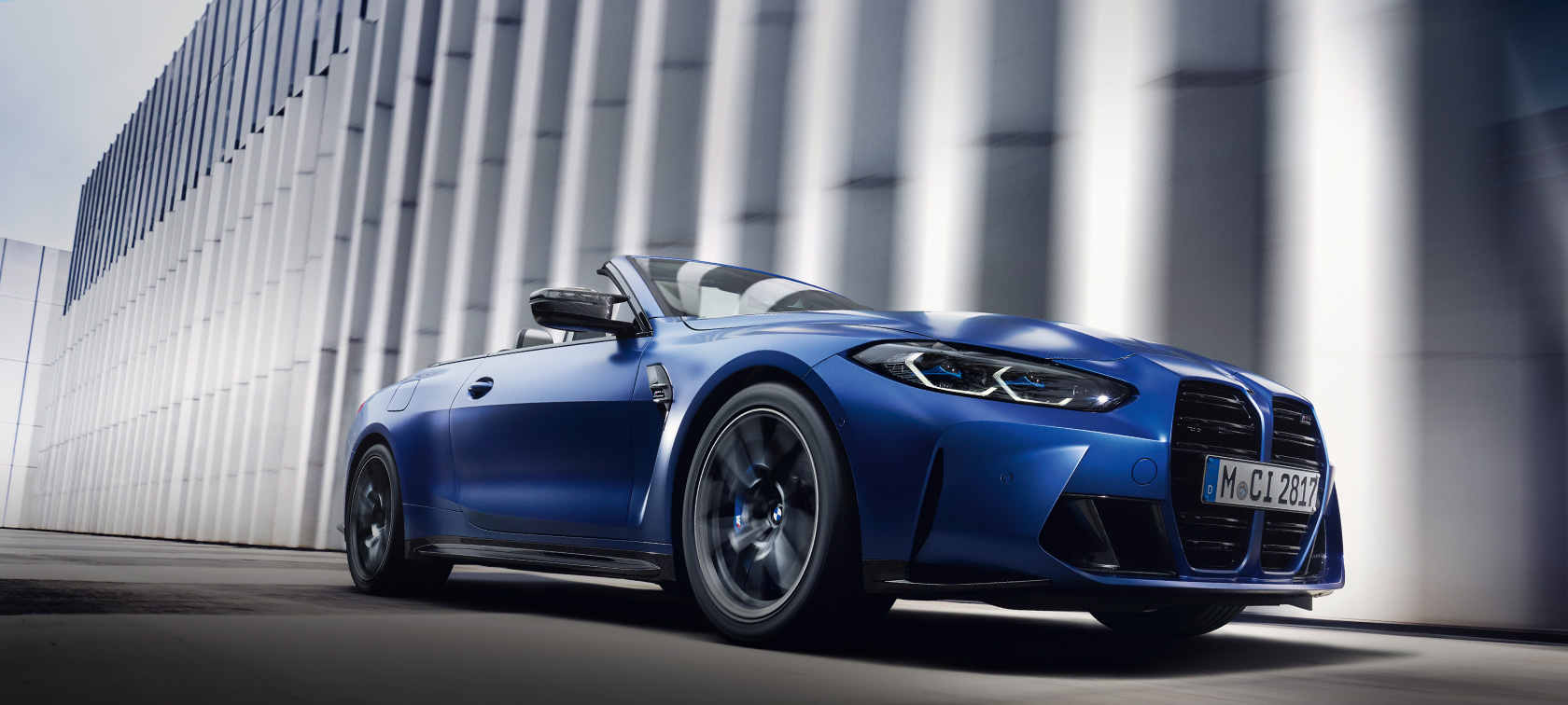 Imagine cu trei sferturi din partea frontală a BMW M4 Competition Cabriolet cu xDrive M G83 2021, BMW Individual Albastru Frozen Portimao, în mişcare