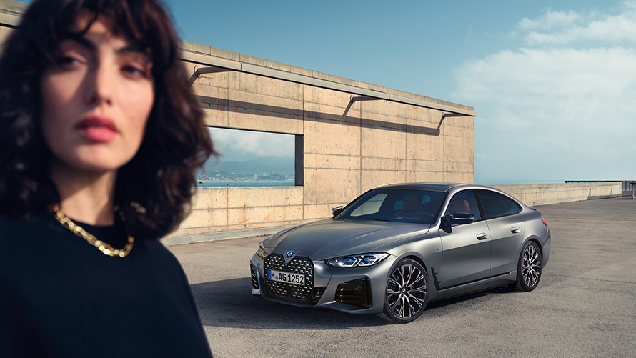 Imagine cu trei sferturi din partea frontală a BMW M440i xDrive Gran Coupé G26 2021, cu un model Imagine cu trei sferturi din partea frontală a modelului BMW M440i xDrive Gran Coupé G26 2021, în Gri Frozen Pure, cu un model