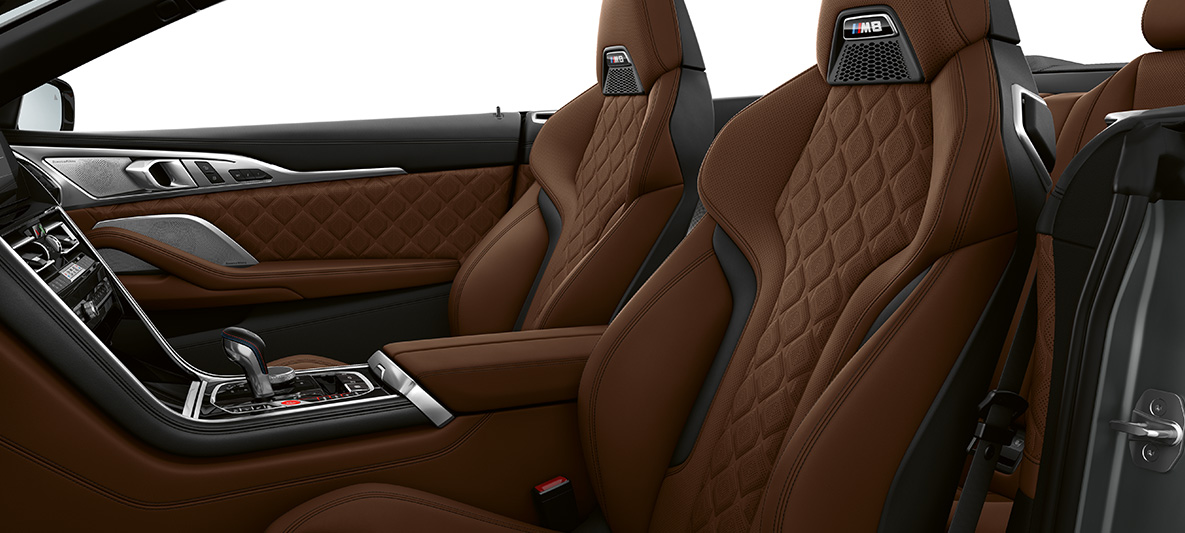 Scaune M Sport cu emblemă „M”. Interiorul BMW M8 Cabriolet cu scaune M Sport îmbrăcate în piele Merino integrală cu granulaţie fină în Maro Taruma.