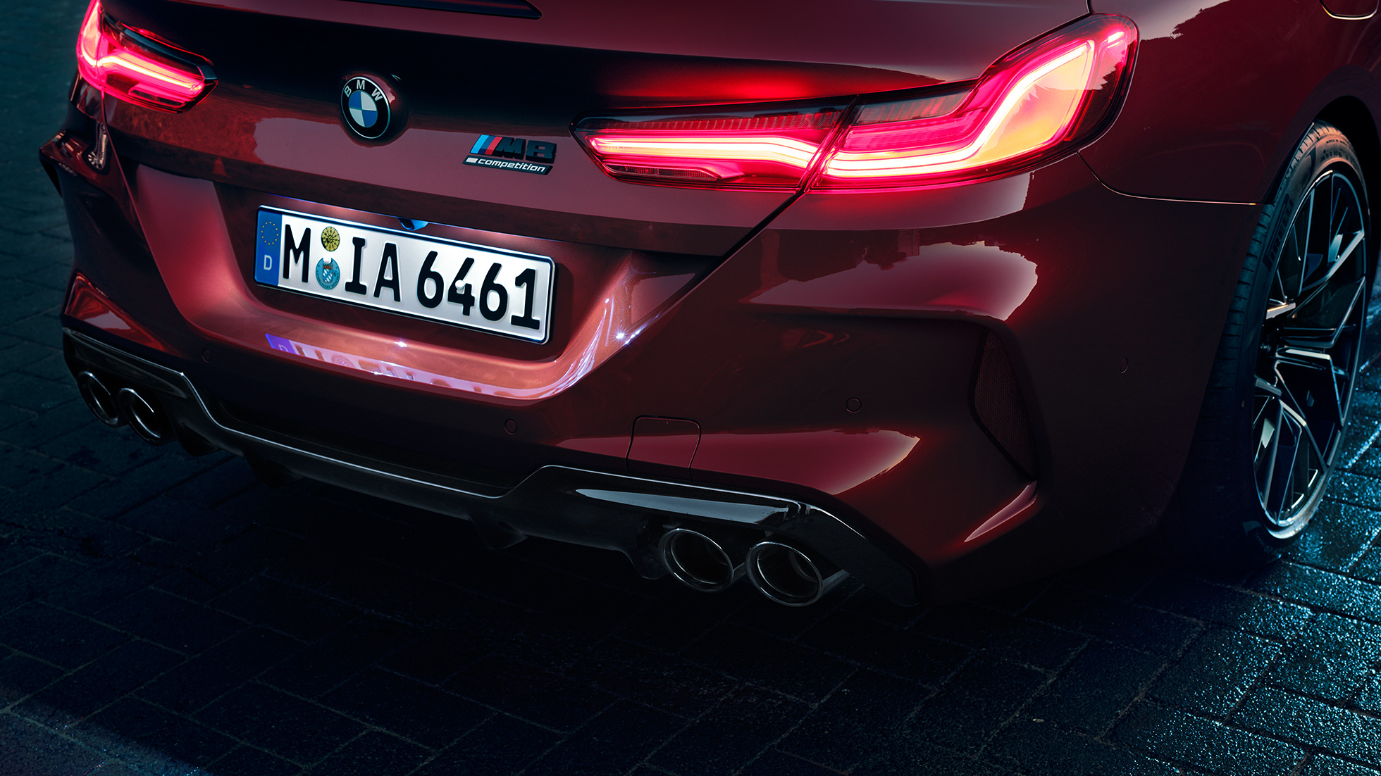 Imagine în prim-plan cu partea spate a BMW M8 Competition Cabriolet. Imagine în prim-plan cu partea spate a BMW M8 Competition Cabriolet în Roşu Motegi metalizat cu stopuri cu tehnologie LED şi inscripţie „M8 Competition”.