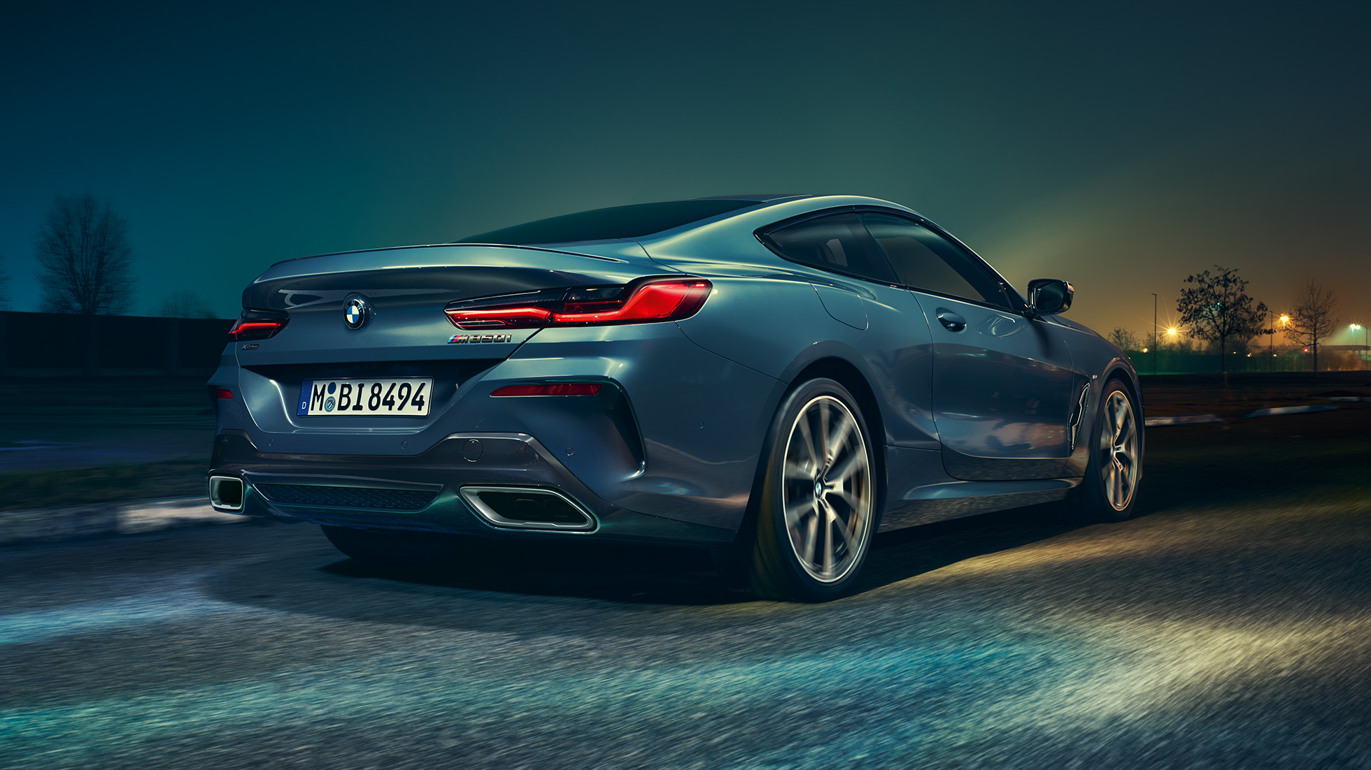 Imagine cu partea spate a BMW M850i xDrive Coupé. Imagine cu partea spate a BMW M850i xDrive Coupé în Albastru Barcelona metalizat, rulând pe timp de noapte.