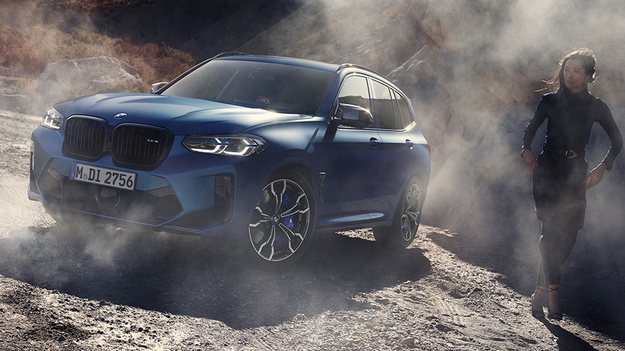 Imagine cu trei sferturi din partea frontală a unui BMW X3 M Competition F97 LCI 2021, staţionând pe teren stâncos Imagine cu trei sferturi din partea frontală a BMW X3 M Competition F97 LCI Facelift 2021 în Albastru Frozen Marina Bay, staţionând pe teren stâncos cu model feminin