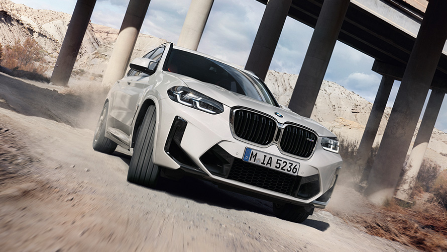 Imagine cu trei sferturi din partea frontală a unui BMW X3 M F97 LCI Facelift 2021 în timp ce intră într-un viraj Imagine cu trei sferturi din partea frontală a unui BMW X3 M F97 LCI Facelift 2021 Alb Alpine în timp ce intră într-un viraj
