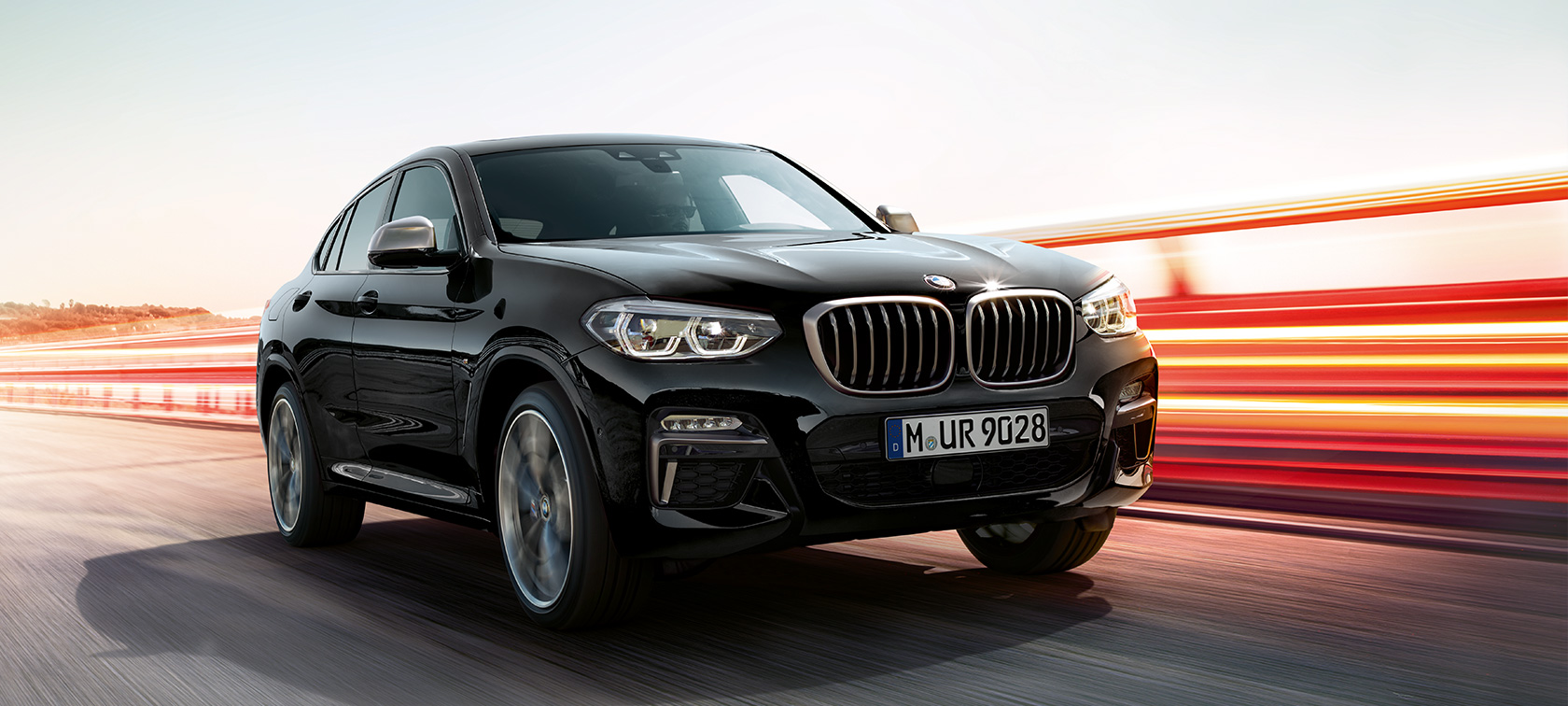 Imagine cu trei sferturi din partea frontală stângă a BMW X4 M40i şi BMW X4 M40d. Imagine cu trei sferturi din partea frontală stângă a BMW X4 M40i şi BMW X4 M40d în Negru Sapphire metalizat cu raze de lumină.