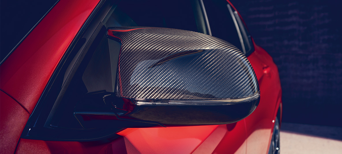 BMW X4 M Competition, cu oglinzi exterioare din carbon. Imagine cu exteriorul BMW X4 M Competition în Roşu Toronto metalizat, cu pachet M din carbon pentru exterior şi oglinzi exterioare din carbon.