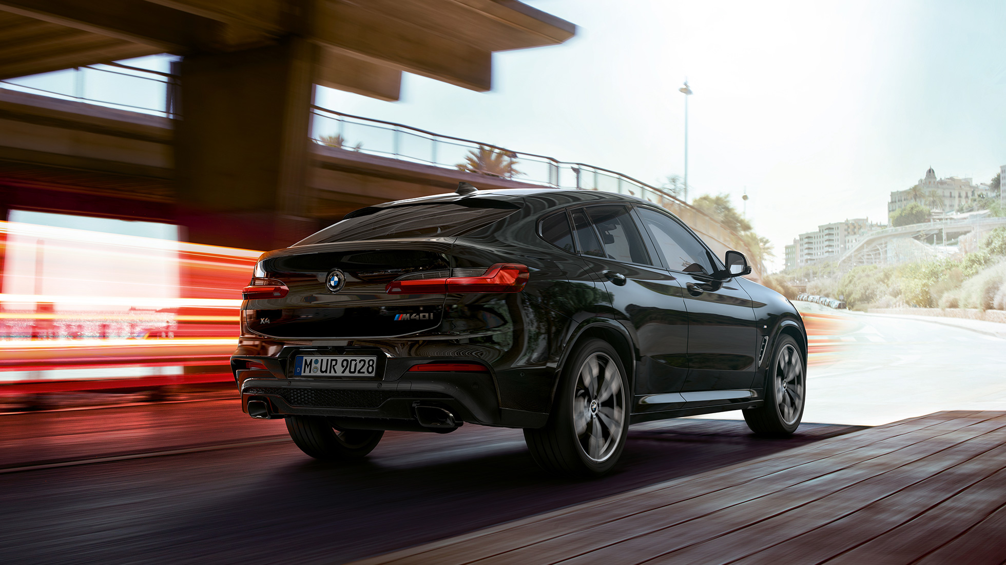 Imagine cu trei sferturi din partea frontală a BMW X4 M40i. Imagine cu trei sferturi din partea frontală exterioară a BMW X4 M40i în Negru Sapphire metalizat cu raze de lumină.