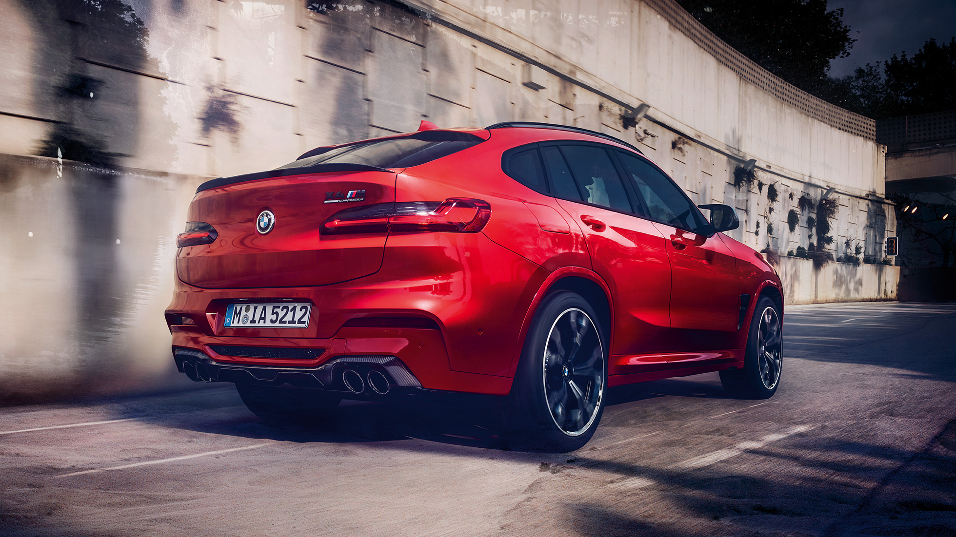 Imagine din lateral cu partea spate a BMW X4 M Competition. Imagine din lateral cu partea spate exterioară a BMW X4 M Competition în Roşu Toronto metalizat.