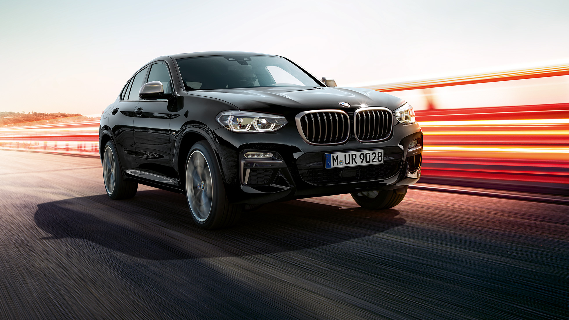Imagine cu trei sferturi din partea frontală a BMW X4 M40i şi BMW X4 M40d. Imagine cu trei sferturi din partea frontală stânga a BMW X4 M40i şi BMW X4 M40d în Negru Sapphire metalizat cu raze de lumină.