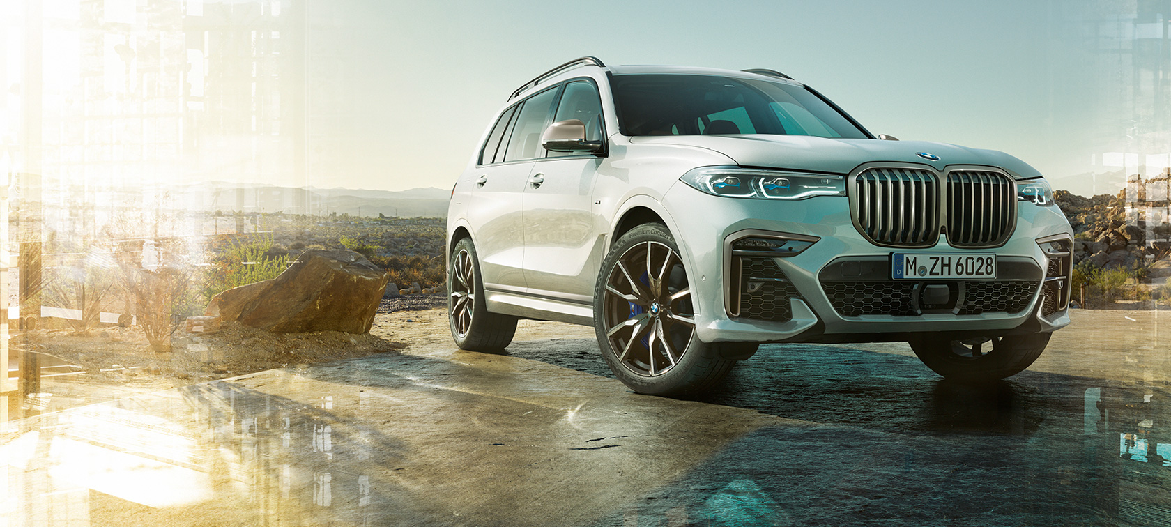 Imagine cu trei sferturi din partea frontală stângă a modelelor BMW X7 M Imagine cu trei sferturi din partea frontală stângă a modelelor BMW X7 M în Alb Mineral, staţionând, G07