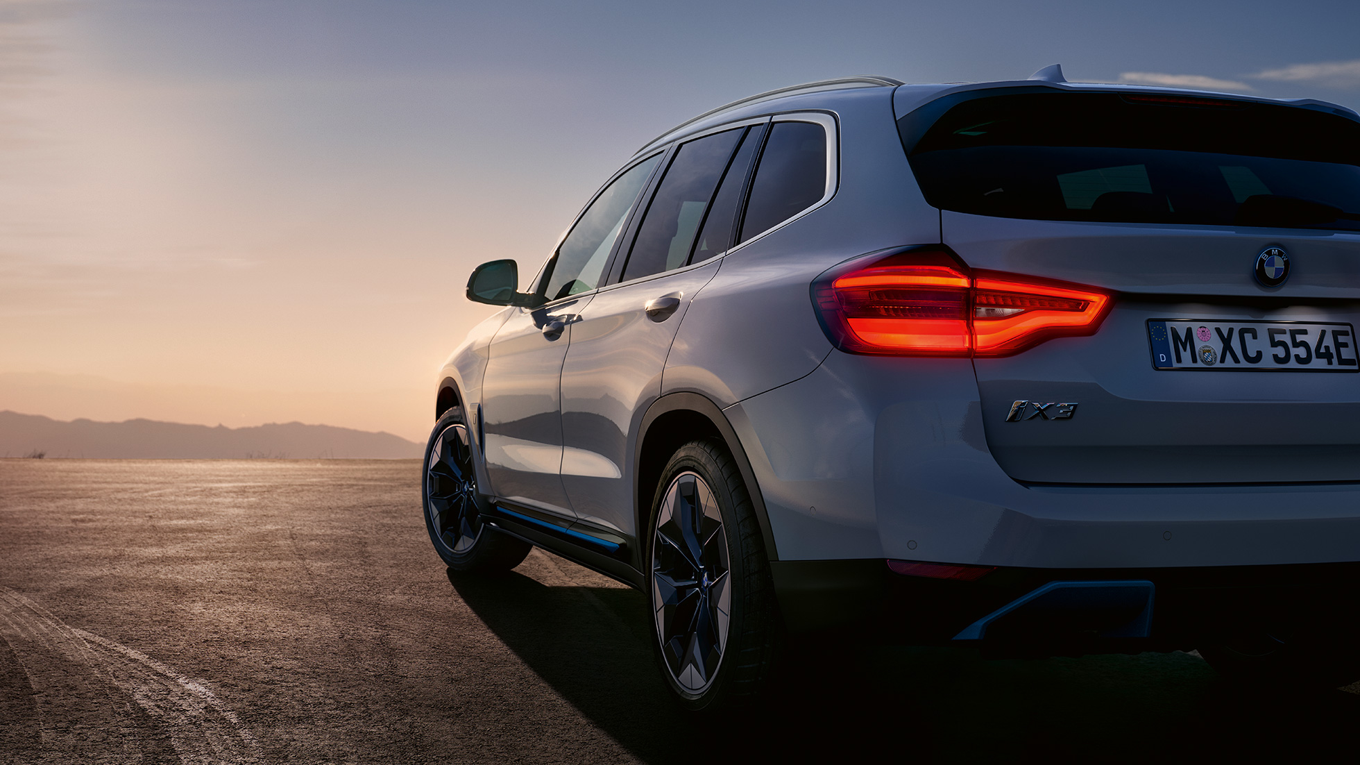 Imagine cu trei sferturi din partea spate a BMW iX3, G08, pe şosea Imagine cu trei sferturi din partea spate a BMW iX3, G08, 2020, în Alb Mineral metalizat, pe şosea