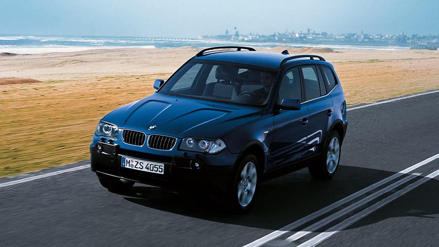 Imagine cu trei sferturi din partea frontală a BMW X3 E83 din prima generaţie în mers pe stradă Imagine cu trei sferturi din partea frontală a BMW Seria X BMW X3 E83 din prima generaţie în mers pe stradă