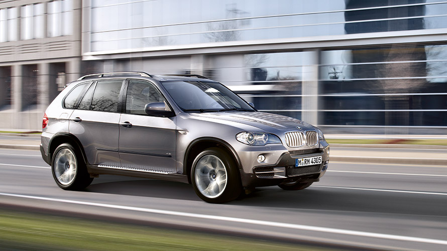 Imagine din partea laterală a BMW X5 E70 din a doua generaţie în mers pe stradă Imagine din partea laterală a BMW Seria X BMW X5 E70 din a doua generaţie în mers pe stradă