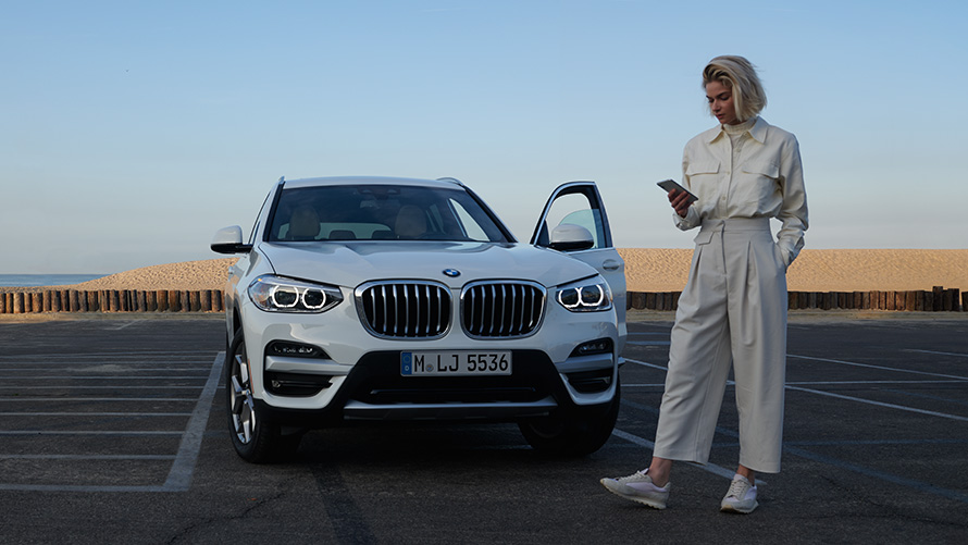 Aplicaţia Brochure pentru BMW X3 G01 2021, femeie lângă un automobil BMW Aplicaţia Brochure pentru BMW X3 G01 2021