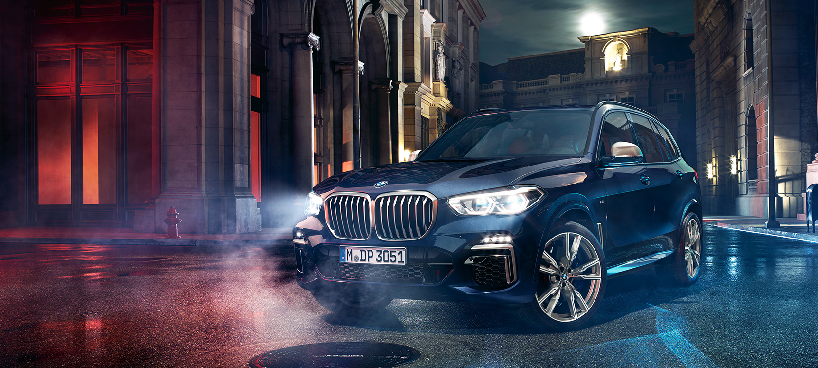 BMW X5 M50d pe şosea BMW X5 M50d staţionează pe şosea pe timp de noapte, cu oraşul pe fundal