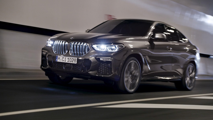 Imagine cu trei sferturi din partea frontală a BMW X6 G06 2019 Imagine cu trei sferturi din partea frontală a BMW X6 G06 2019, rulând în faţa unui peisaj urban