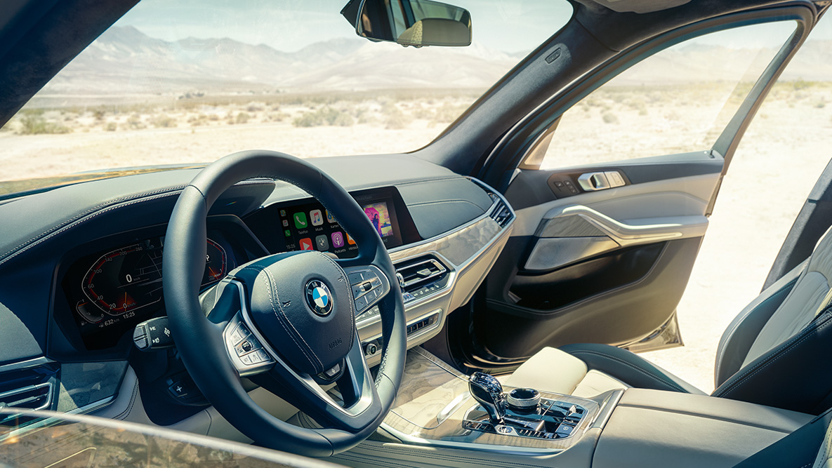 Interiorul BMW X7 Interiorul BMW X7: imagine din exterior cu primul rând de scaune cu perspectivă asupra volanului, a panoului de instrumente şi a scaunelor din piele