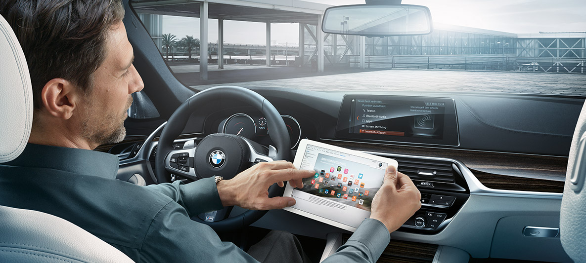 Imagine cu un bărbat aflat la volanul unui automobil BMW, uitându-se pe o tabletă. Imagine cu un bărbat aflat la volanul unui automobil BMW, uitându-se pe o tabletă.