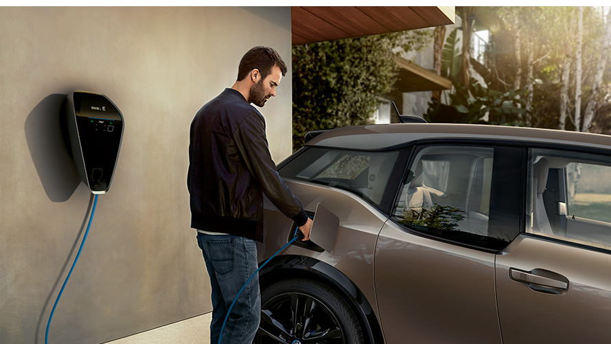 Un bărbat încărcând un BMW i3s la staţia de încărcare Imagine cu un bărbat încărcând un BMW i3s la staţia de încărcare
