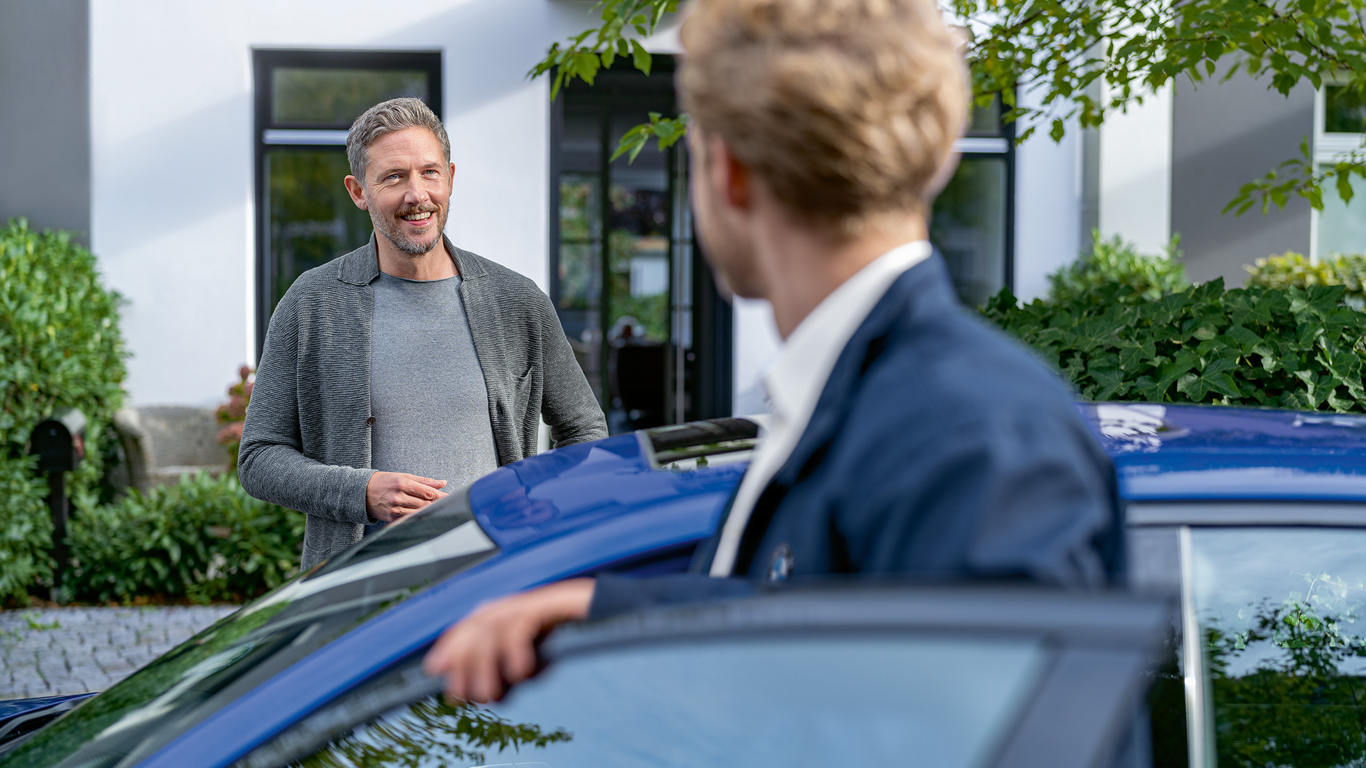 BMW Value Service Un client de service BMW priveşte prin portiera deschisă a automobilului său BMW