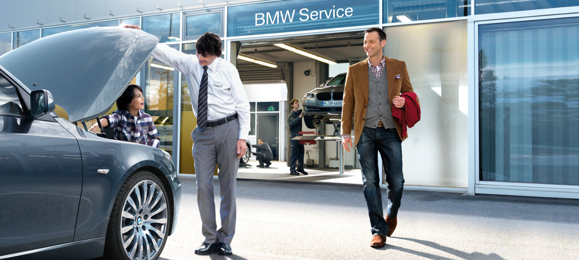 Imagine cu un bărbat, fiul său şi un angajat BMW privind sub capota unui automobil BMW. Imagine cu un bărbat, fiul său şi un angajat BMW privind sub capota unui automobil BMW.