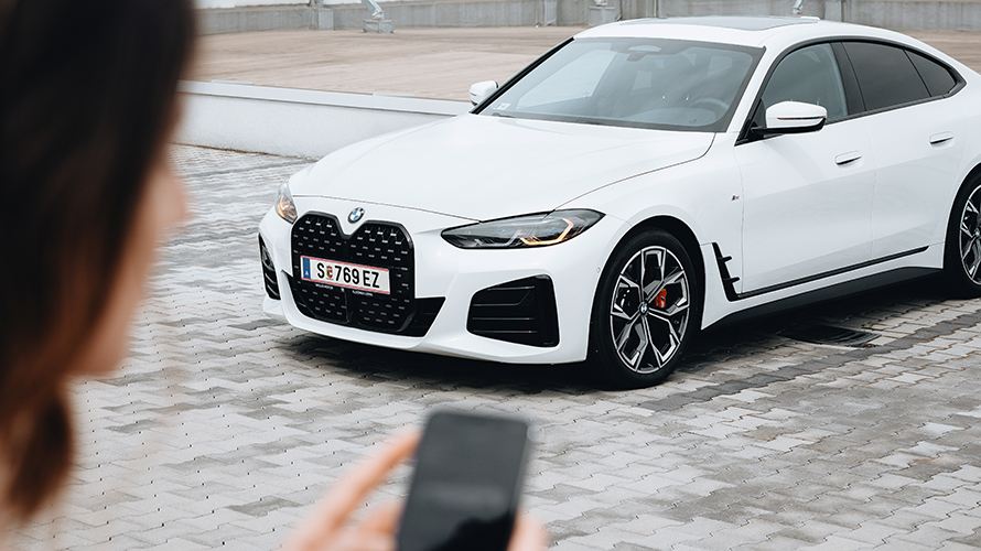 Femeie care îşi foloseşte smartphone-ul. Prim plan pe BMW i4. Femeie care îşi foloseşte smartphone-ul. Prim plan pe BMW i4.