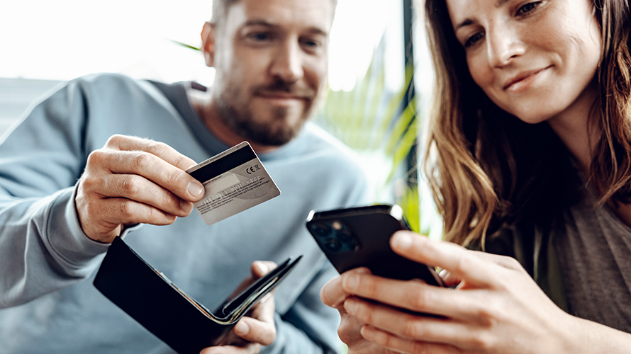 Bărbat şi femeie care navighează pe un smartphone. Bărbat care ţine un card. Bărbat şi femeie care navighează pe un smartphone. Bărbat care ţine un card.