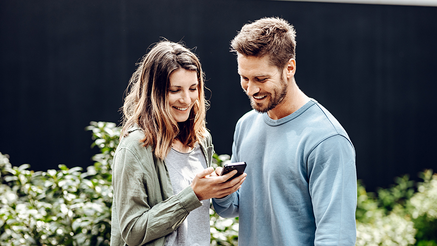 Bărbat şi femeie care privesc către smartphone-ul femeii. El îi arată ceva pe ecran. Bărbat şi femeie care privesc către smartphone-ul femeii. El îi arată ceva pe ecran.